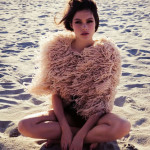 girl with a feather coat on the beach
